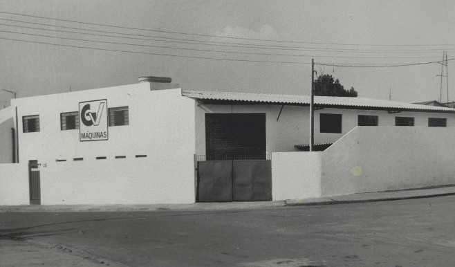 Fachada antiga da fábrica da GV Máquinas, com o logotipo GV na parede, em foto de arquivo em preto e branco